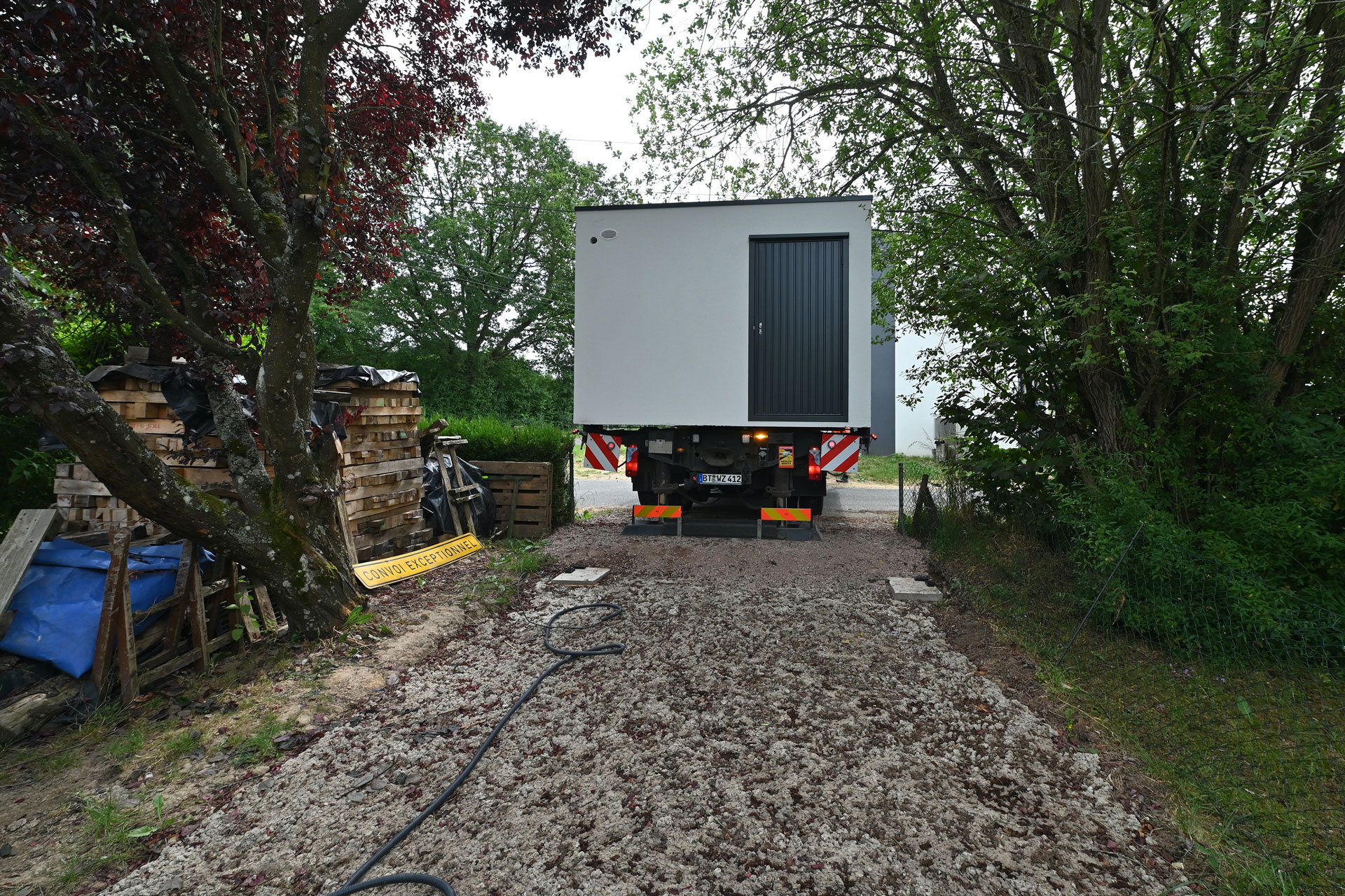 Anlieferung einer Fertiggarage aus Beton mit Spezial-LKW durch schmale Zufahrt – Vorbereitung für fachgerechte Aufstellung auf dem Grundstück