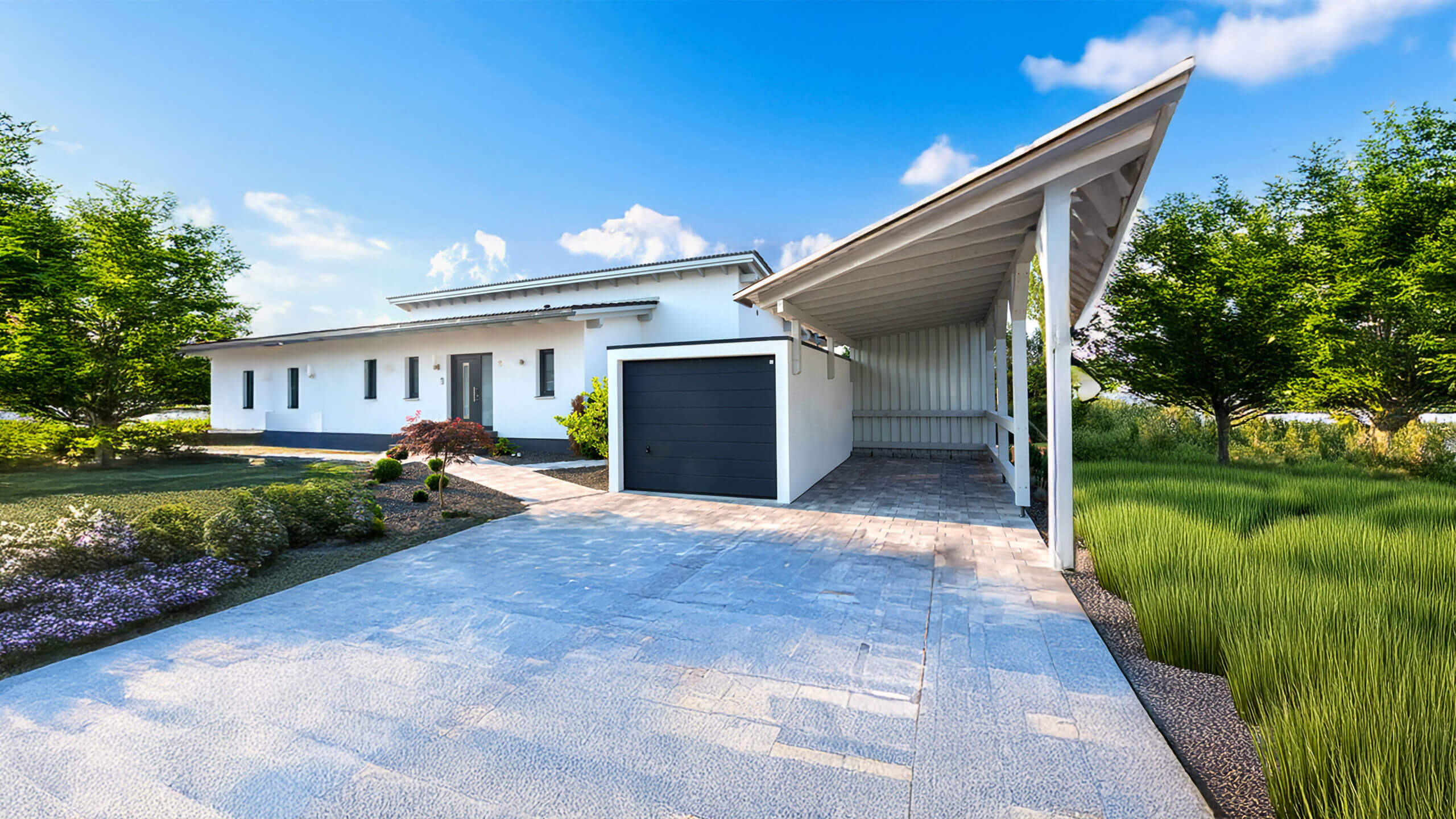 Einzelgarage mit schwarzem Sektionaltor neben einem Einfamilienhaus mit Carport und Garten vor blauem Himmel.