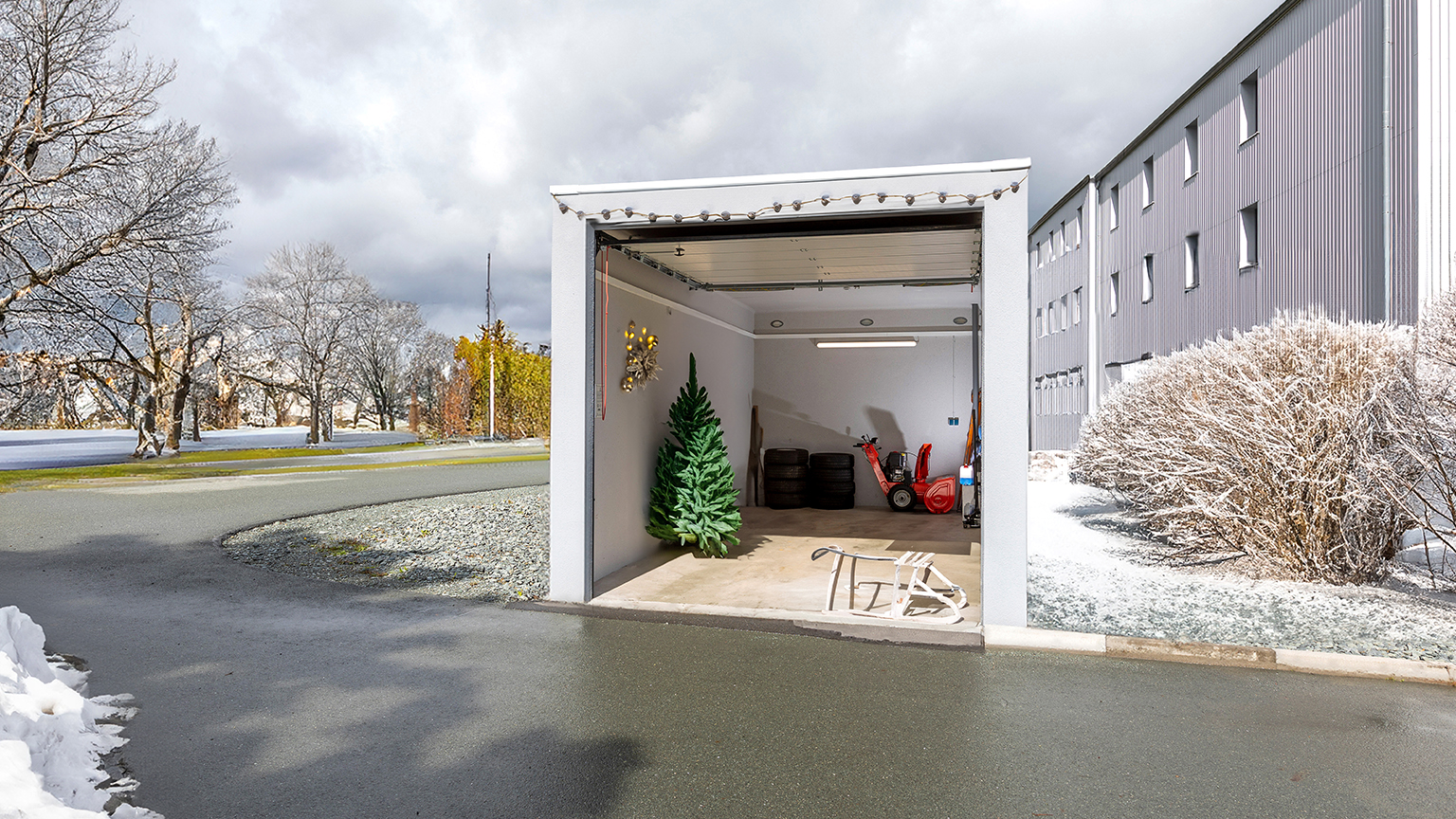 Weihnachtlich dekorierte Garage mit Schneefräse, Tannenbaum und Schlitten – Winterlager und Stauraum.