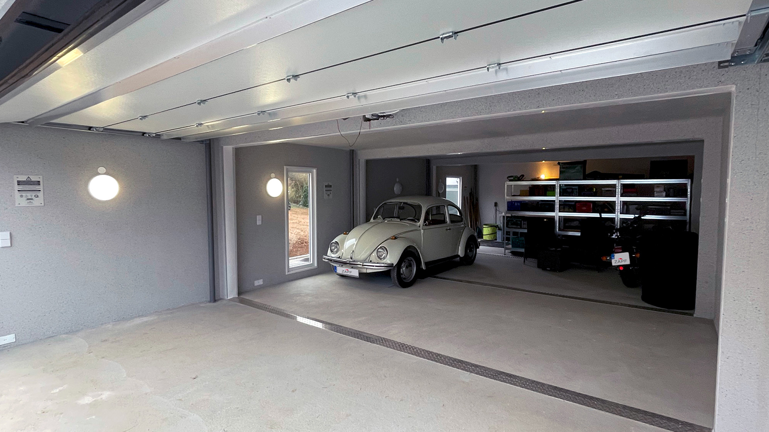 Geräumige Großraumgarage mit Oldtimer, Motorroller, Aufsitzrasenmäher und Anhänger – ordentlich eingerichteter Innenraum.