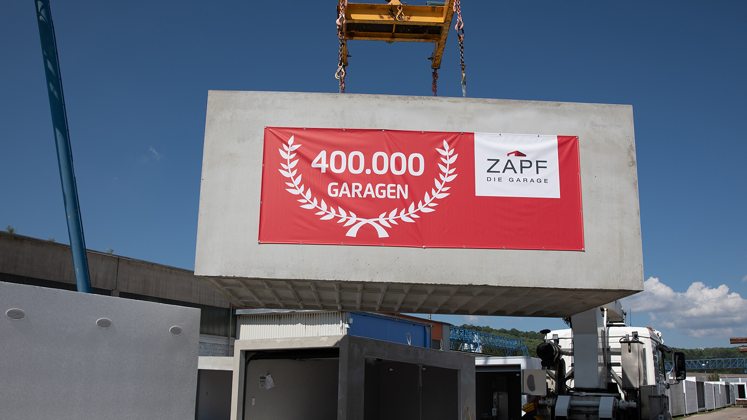 Fertiggarage mit Jubiläumsbanner „400.000 Garagen“ wird per Kran angeliefert.