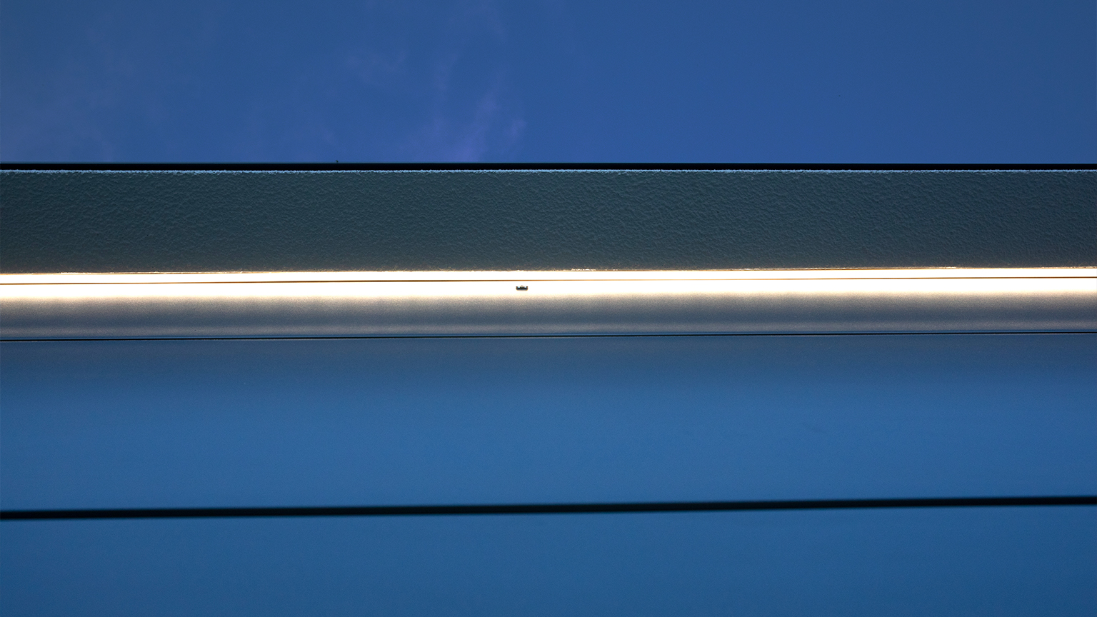 Detailaufnahme einer LED-Lichtleiste oberhalb eines Garagentors bei Dämmerung.