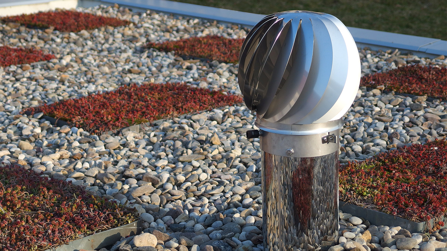 Drehbare Ökogaragenlüfter auf begrüntem Garagendach mit Kies