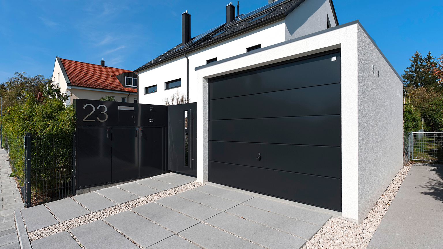zapf_blog_beitragstitel_bundesland Design-Fertiggarage mit schwarzem Sektionaltor und Hauszugang an moderner Stadtvilla.