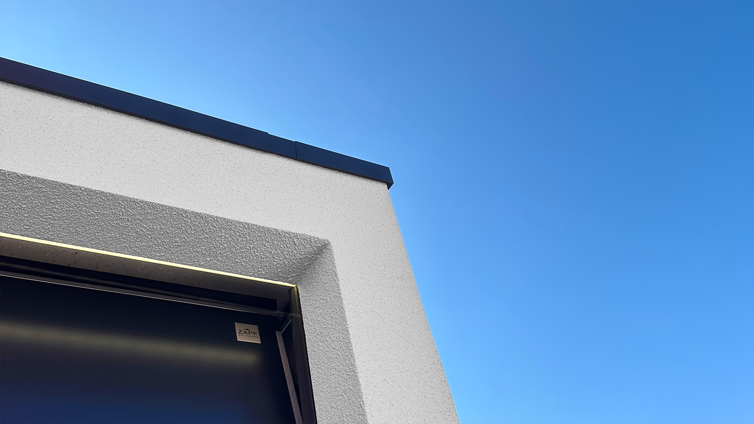 Detailansicht einer modernen Garagenecke mit LED-Lichtleiste und ZAPF-Logo unter klarem Himmel.