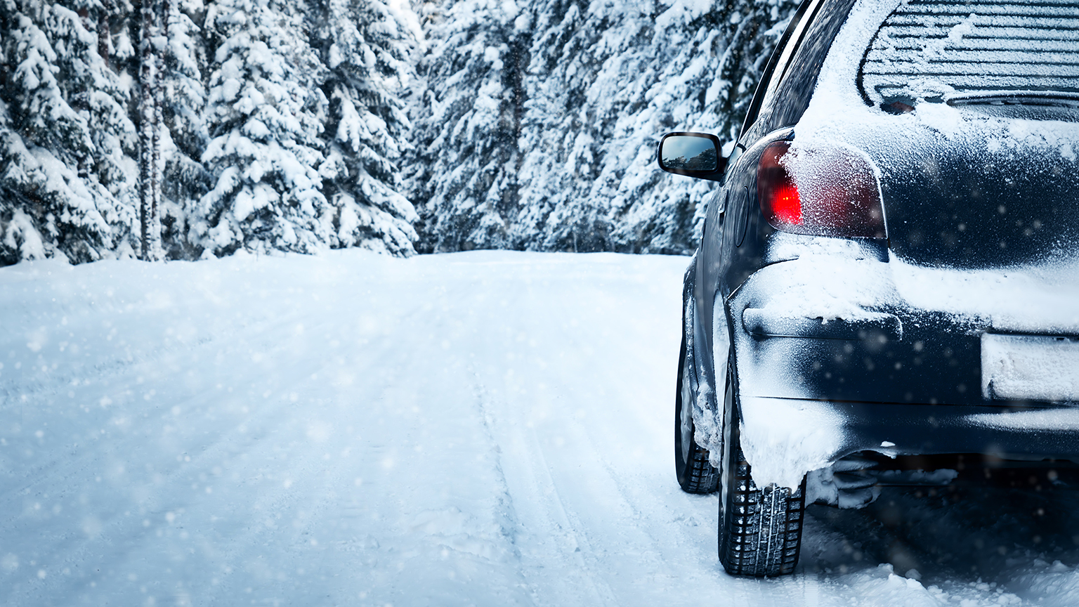 zapf_blog_beitragstitel_freizeit Auto auf verschneiter Waldstraße, mit Schnee bedeckt und Rücklicht aktiviert.