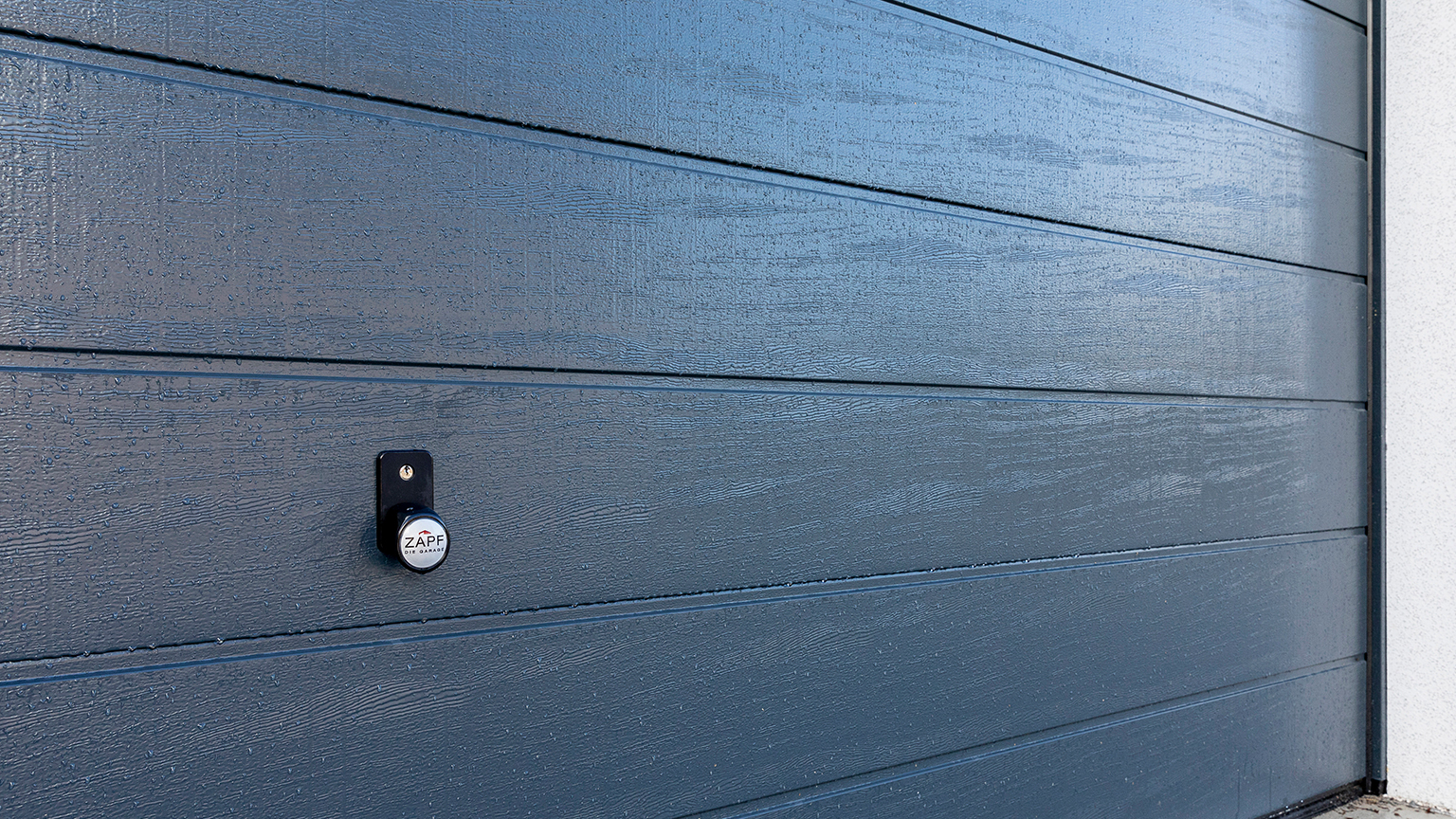 Detailaufnahme eines dunklen Sektionaltores mit Zapf Schloss und sichtbarer Oberflächenstruktur.