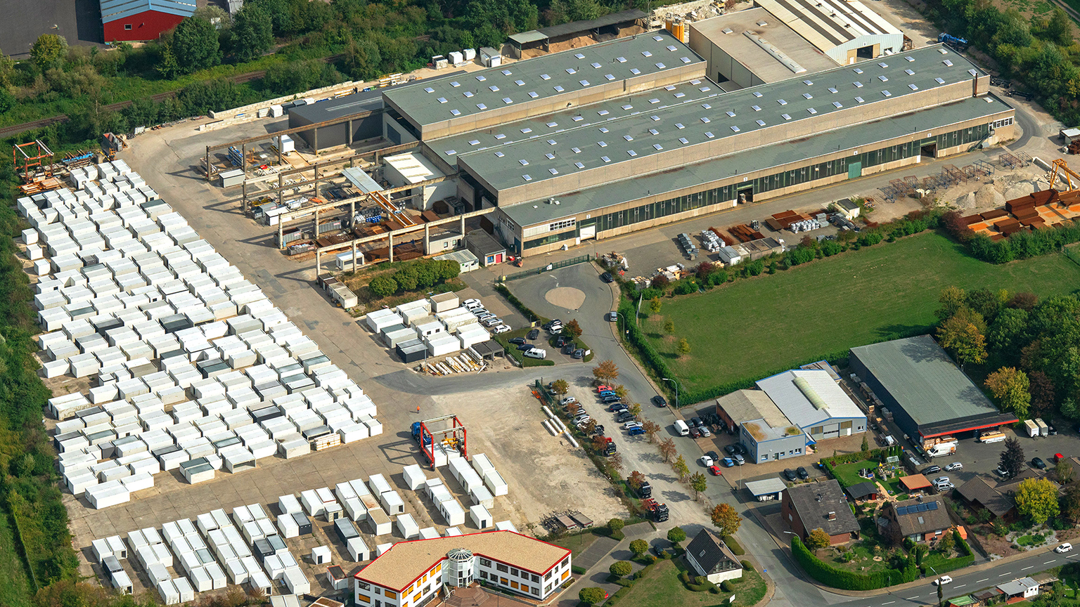 Luftaufnahme eines Produktionsgeländes mit Lagerfläche für Fertiggaragen und Industriehallen.