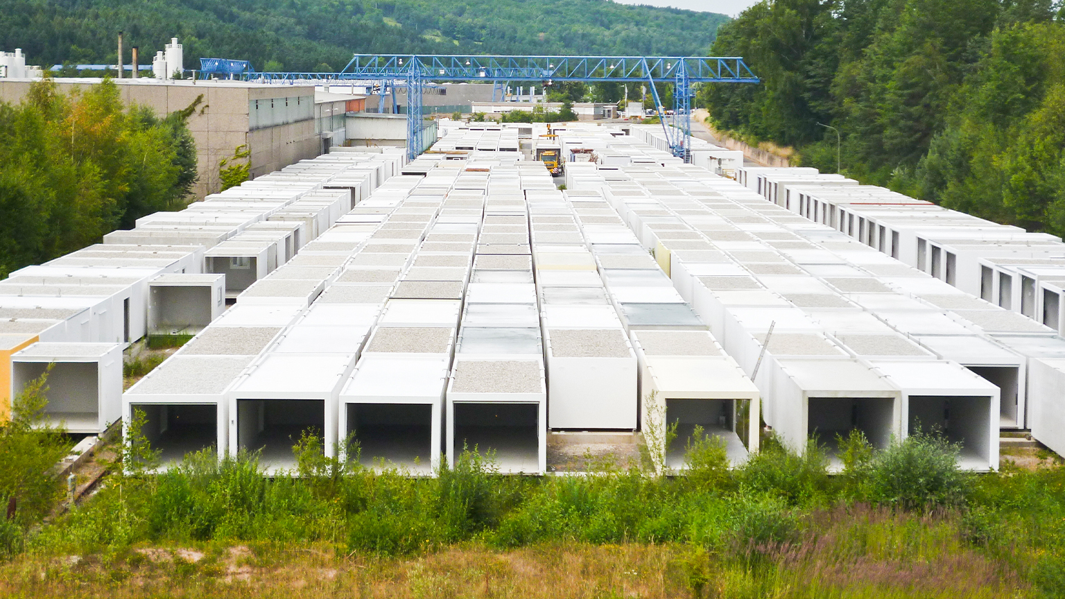 Großes Lagergelände mit zahlreichen Fertiggaragen in Reihung, umgeben von Wald und Industriehallen.
