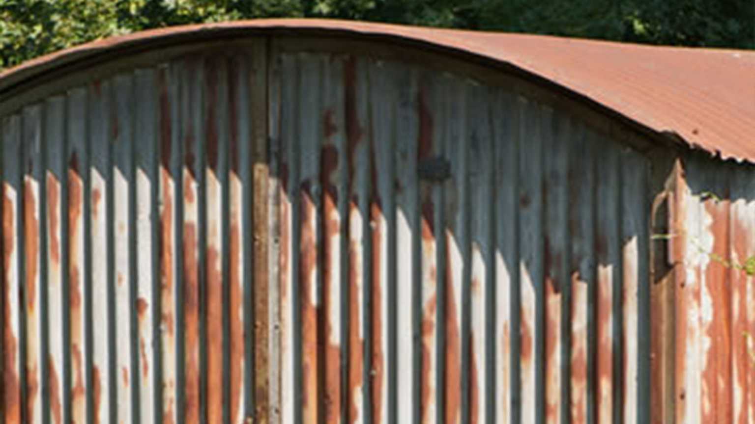 Nahaufnahme einer alten, stark verrosteten Wellblechgarage mit Runddach.