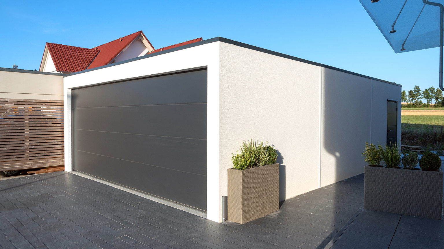 Großraumgarage mit strukturierter Holzoptik-Fassade, integriert in Einfamilienhaus auf dem Land.