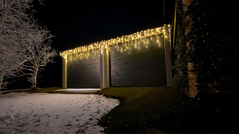Auto in geöffneter Fertiggarage von ZAPF, umgeben von verschneiter Winterlandschaft.