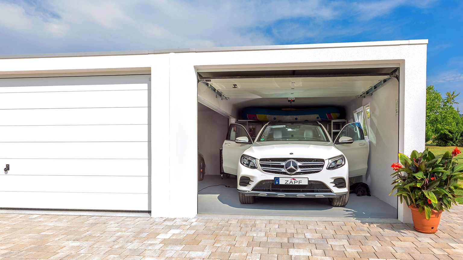 Weißer Mercedes SUV mit geöffneten Türen in heller ZAPF Garage, SUP-Board an der Decke verstaut.