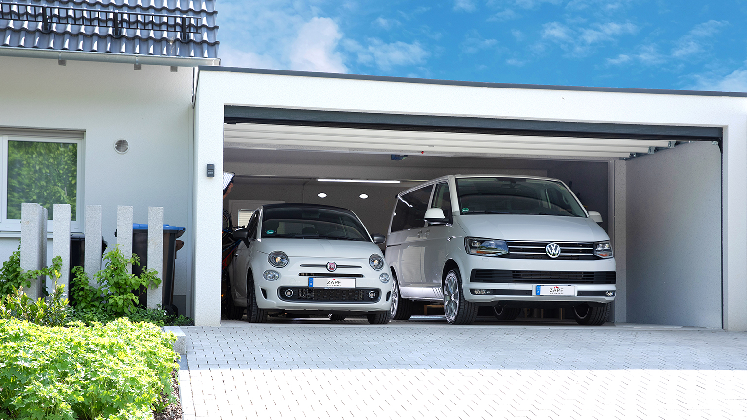 Zwei Fahrzeuge, Fiat 500 und VW Bus, parken nebeneinander in geöffneter Doppelgarage von ZAPF.