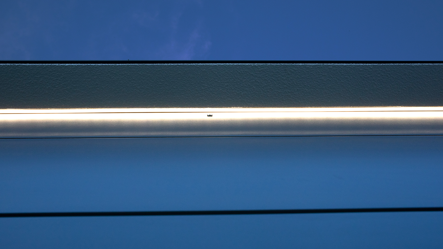 Detailaufnahme einer LED-Lichtleiste über dem Garagentor bei Dämmerung.