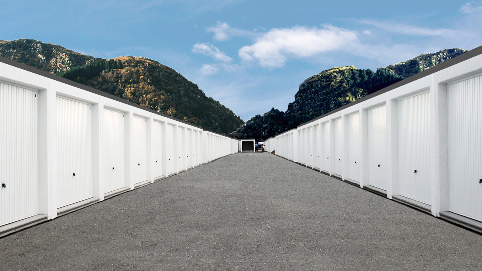 Reihengaragenanlage mit weißen Garagen vor Bergkulisse unter blauem Himmel.