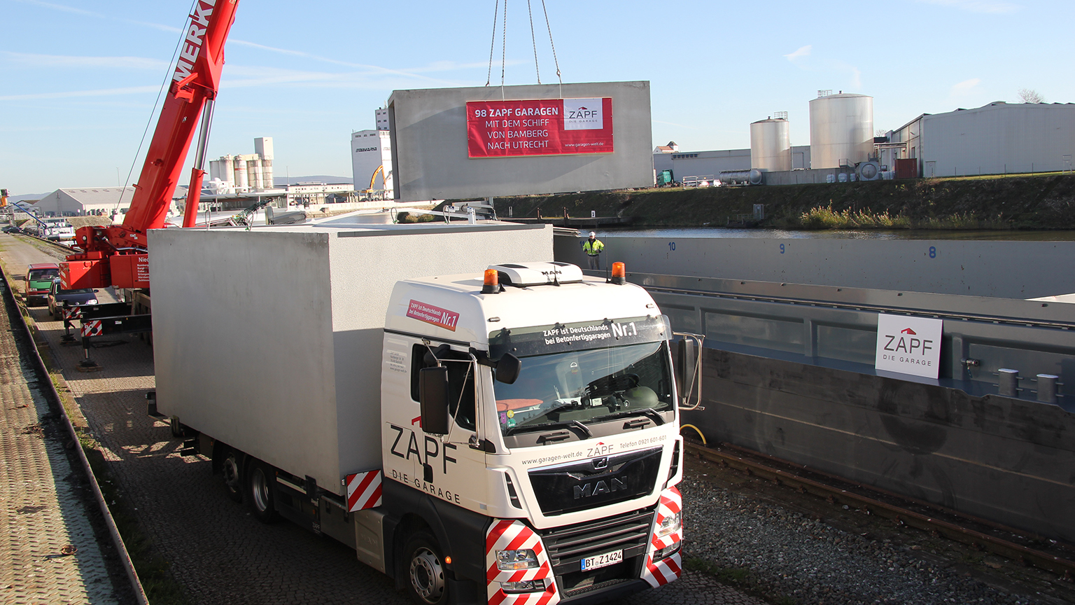 Betonfertiggarage von ZAPF wird mit Kran vom Lkw auf ein Schiff verladen.