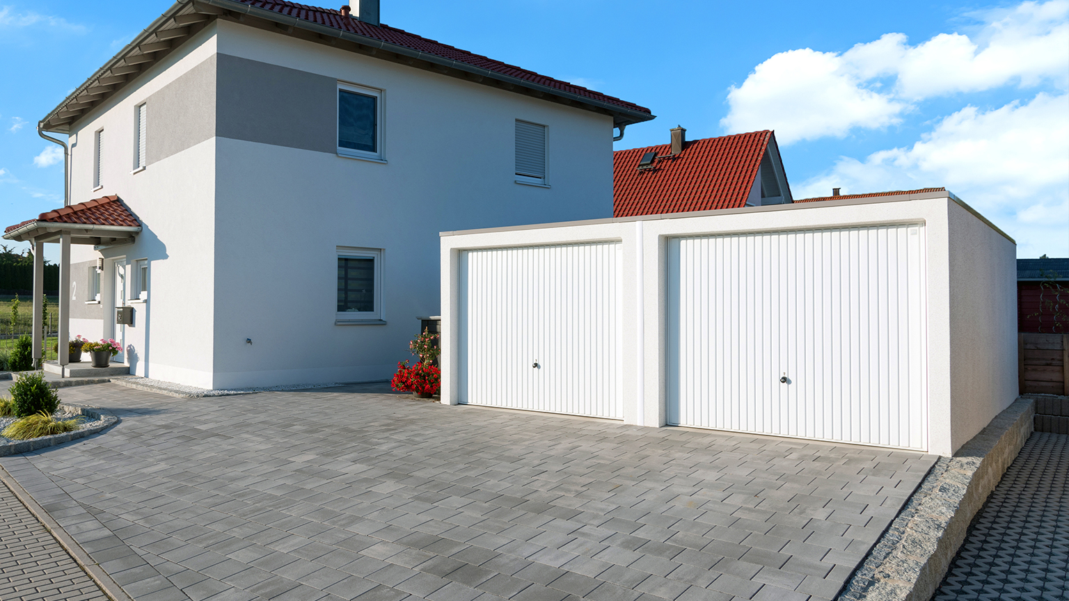 Doppelgarage von ZAPF vor einem modernen Einfamilienhaus mit großzügiger Einfahrt aus Pflastersteinen.