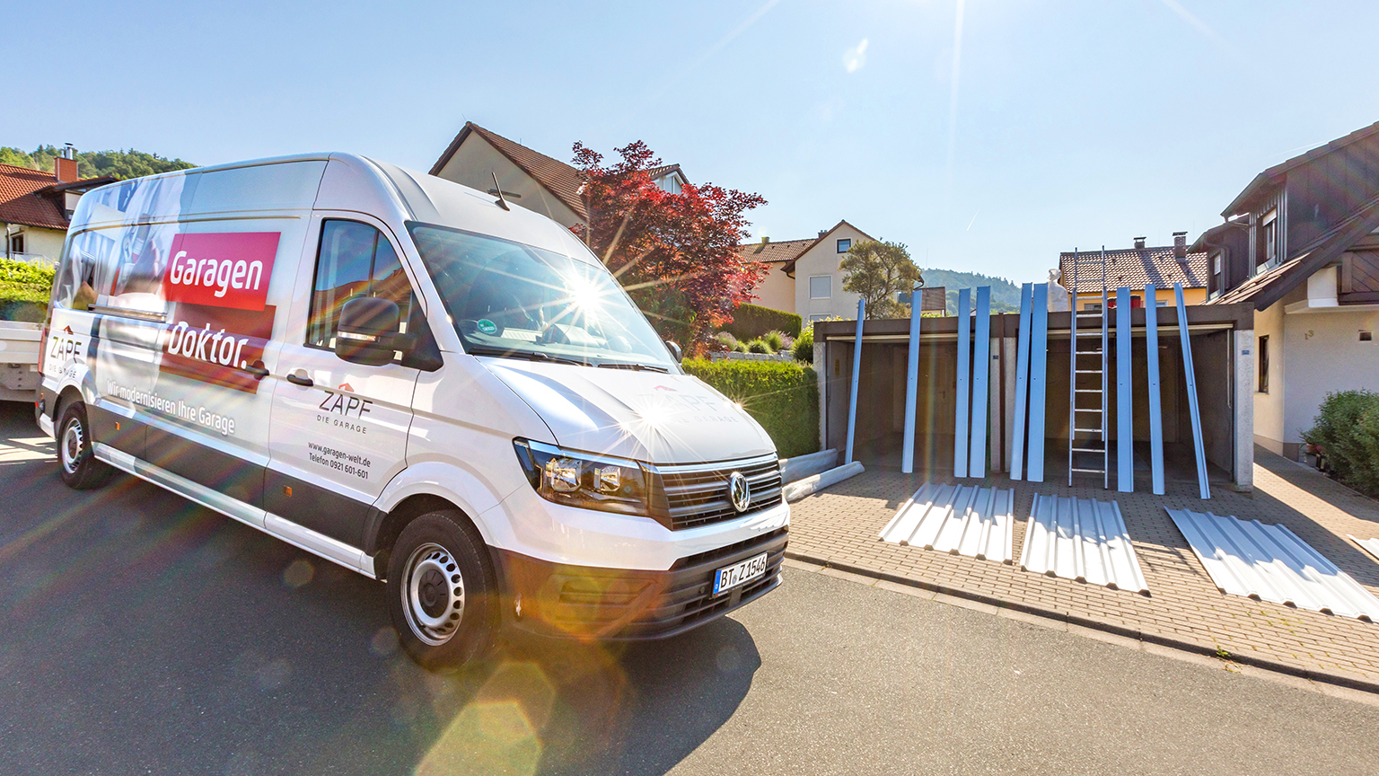 zapf_blog_beitragstitel_anleitung Servicefahrzeug „Garagen Doktor“ vor Garagen mit bereitgelegten Bauteilen zur Sanierung.