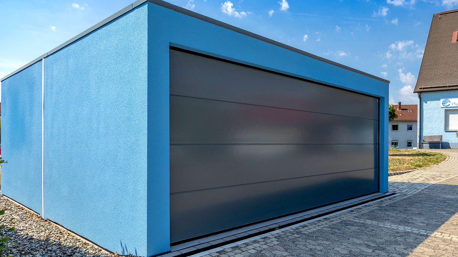 Moderne Großraumgarage mit blauer Fassade und dunklem Sektionaltor.