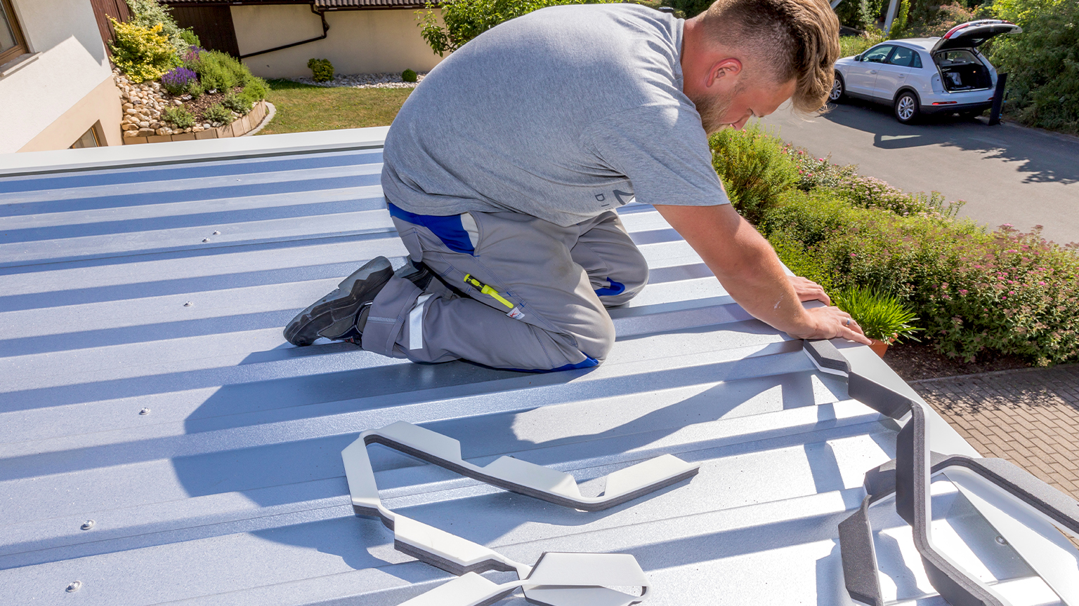 zapf_blog_beitragstitel_herbst_abdichten Mann arbeitet auf Blechdach einer Garage und bringt Kantteile an.