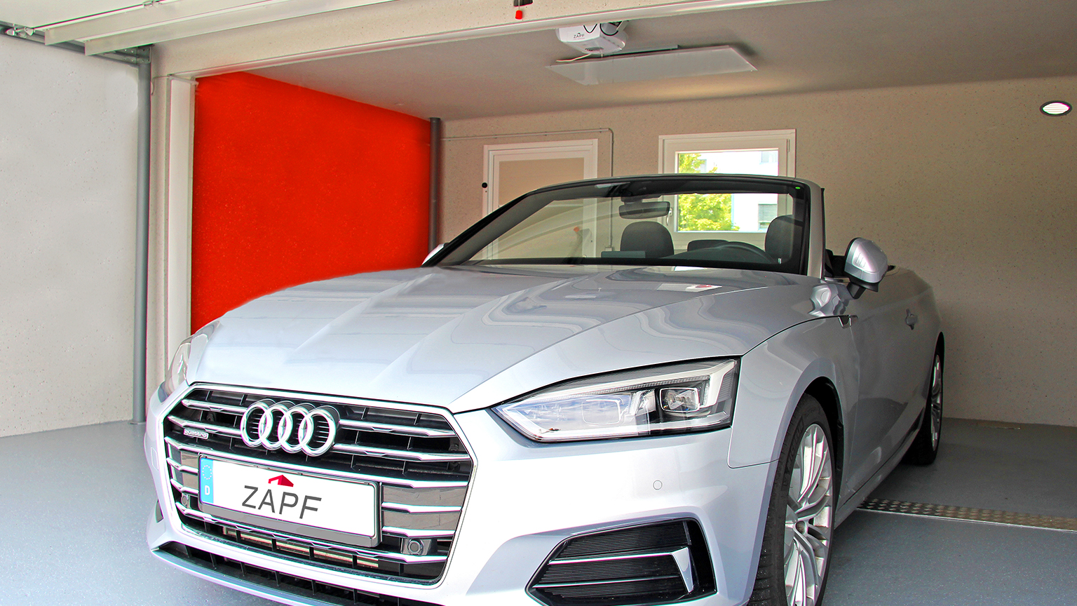 zapf_blog_beitragstitel_innenraum Silbernes Audi Cabriolet steht in einer modernen Garage mit roter Rückwand.