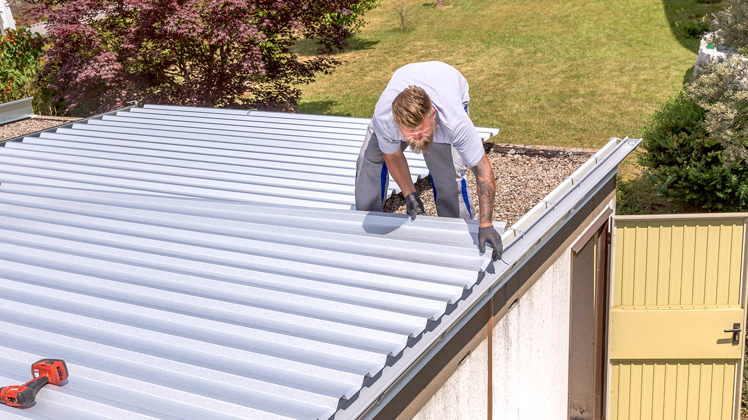 Handwerker richtet Trapezblech auf Garagendach aus.
