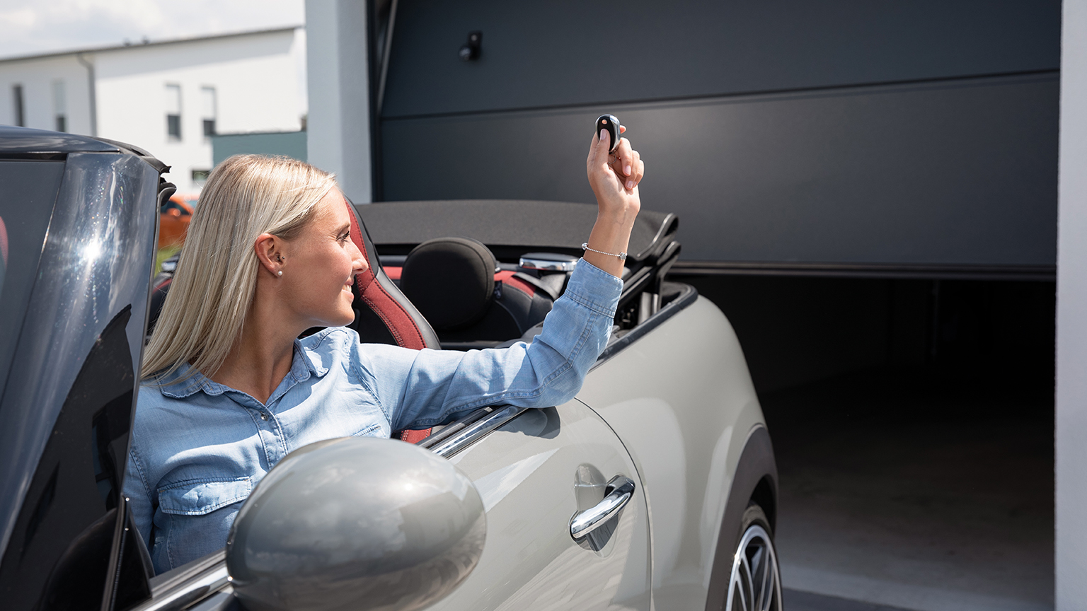 zapf_blog_beitragstitel_oeffner Frau im Cabrio öffnet mit Fernbedienung ein Garagentor.