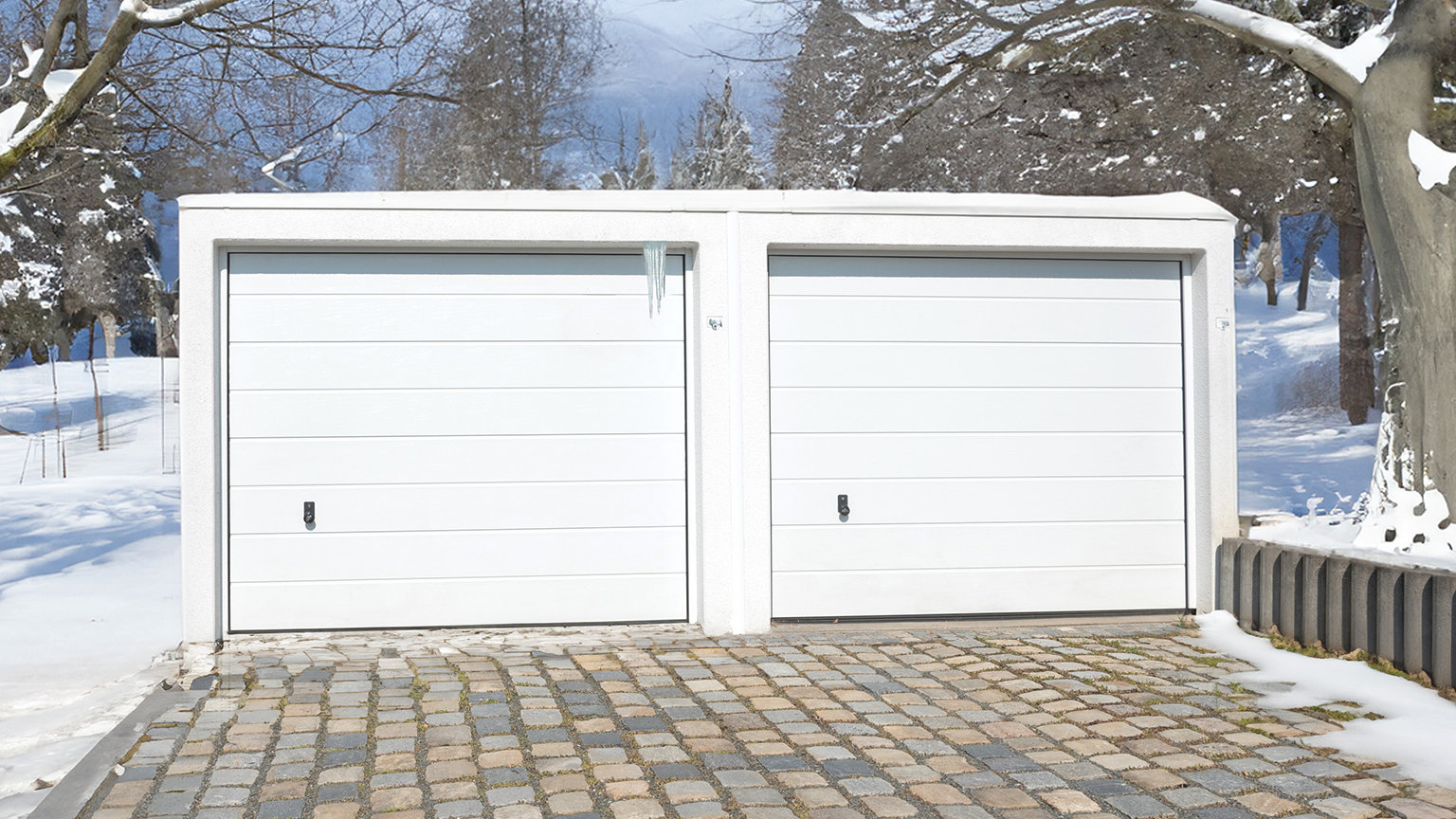 zapf_blog_beitragstitel_renovieren Doppelgarage mit weißen Toren im verschneiten Außenbereich.