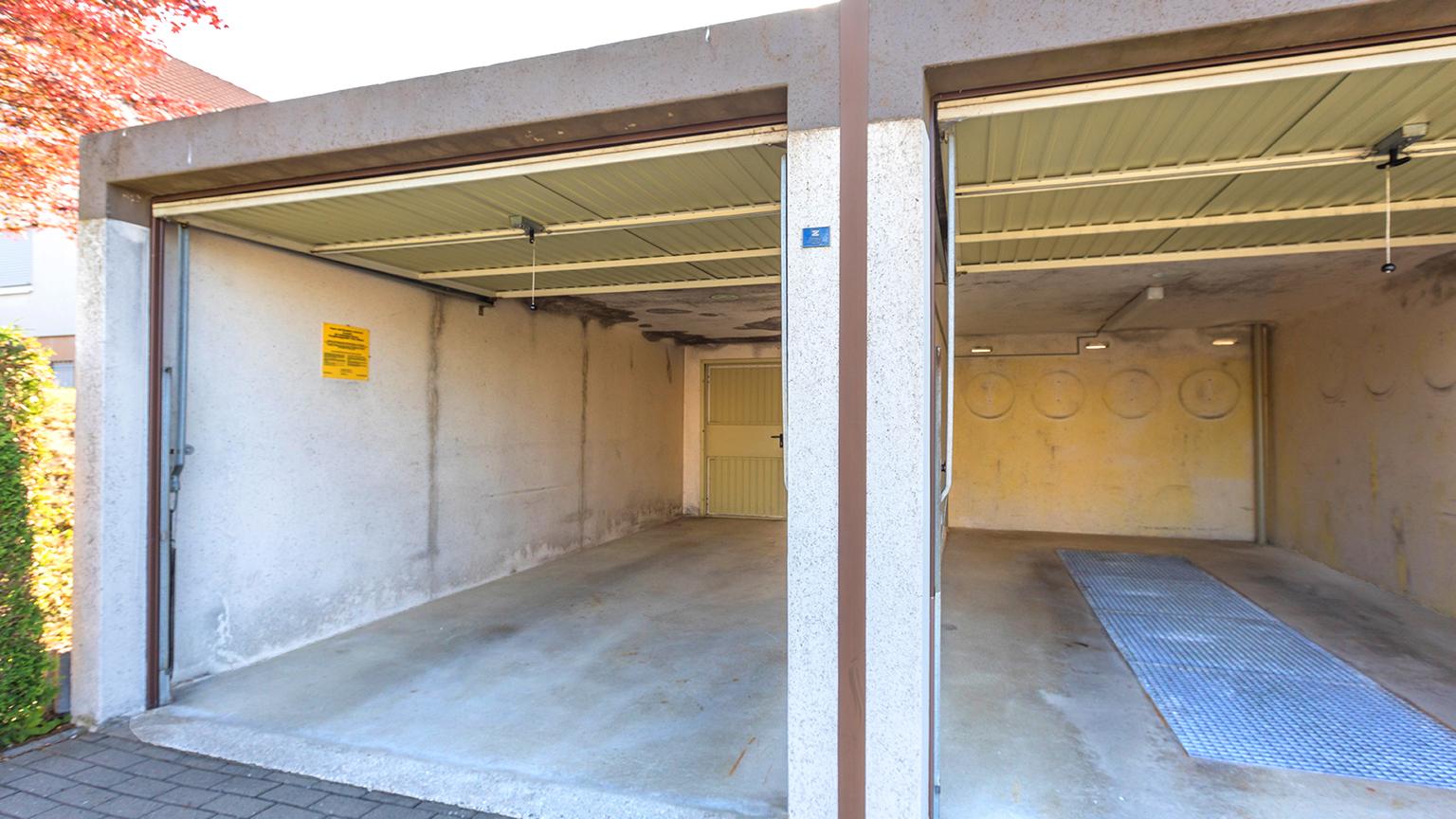 Geöffnete Doppelgarage mit sichtbar abgenutzten Wänden und Decke.