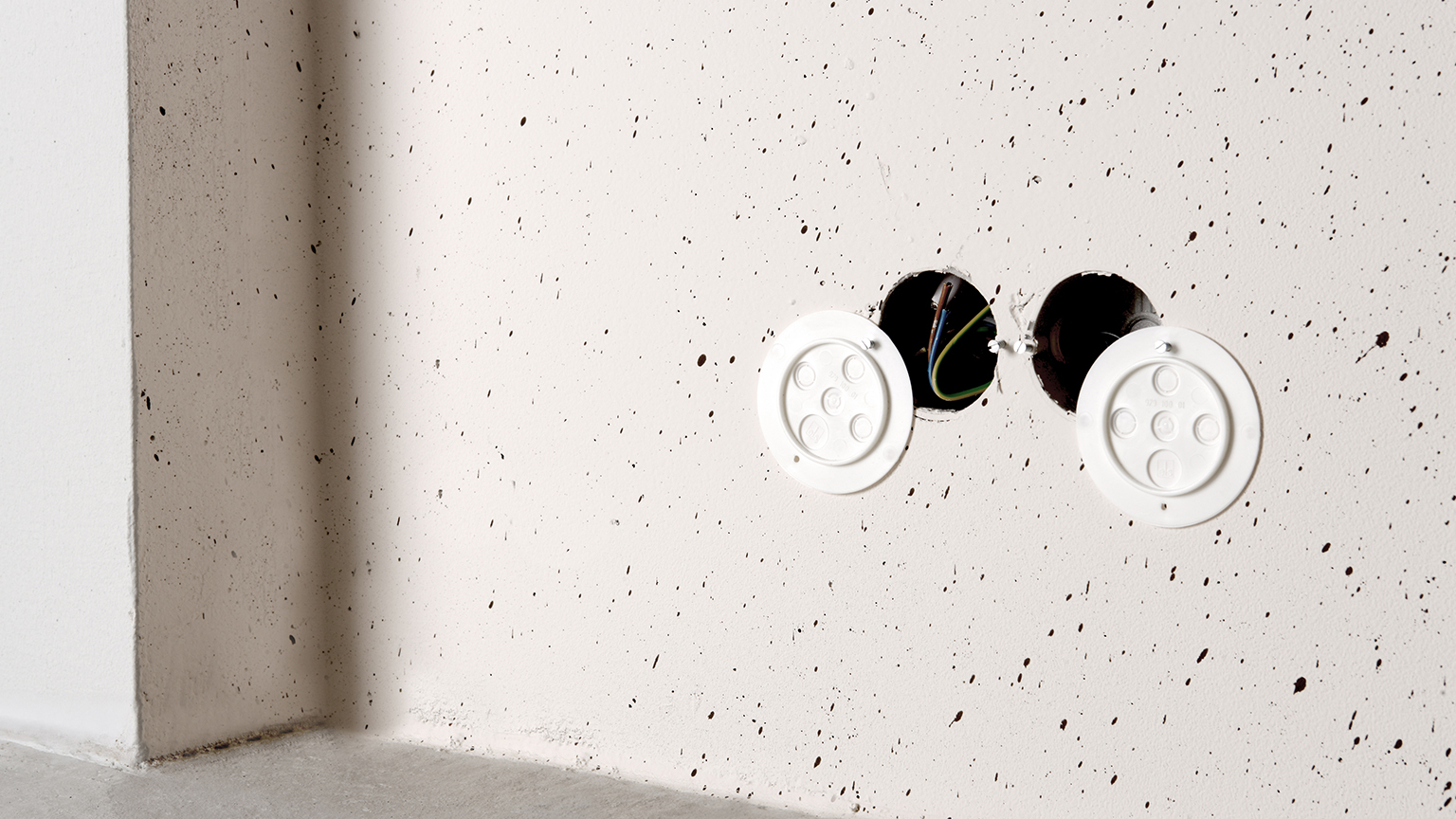 zapf_blog_beitragstitel_strom Nahaufnahme zweier offener Steckdosenanschlüsse in gespachtelter Wand.