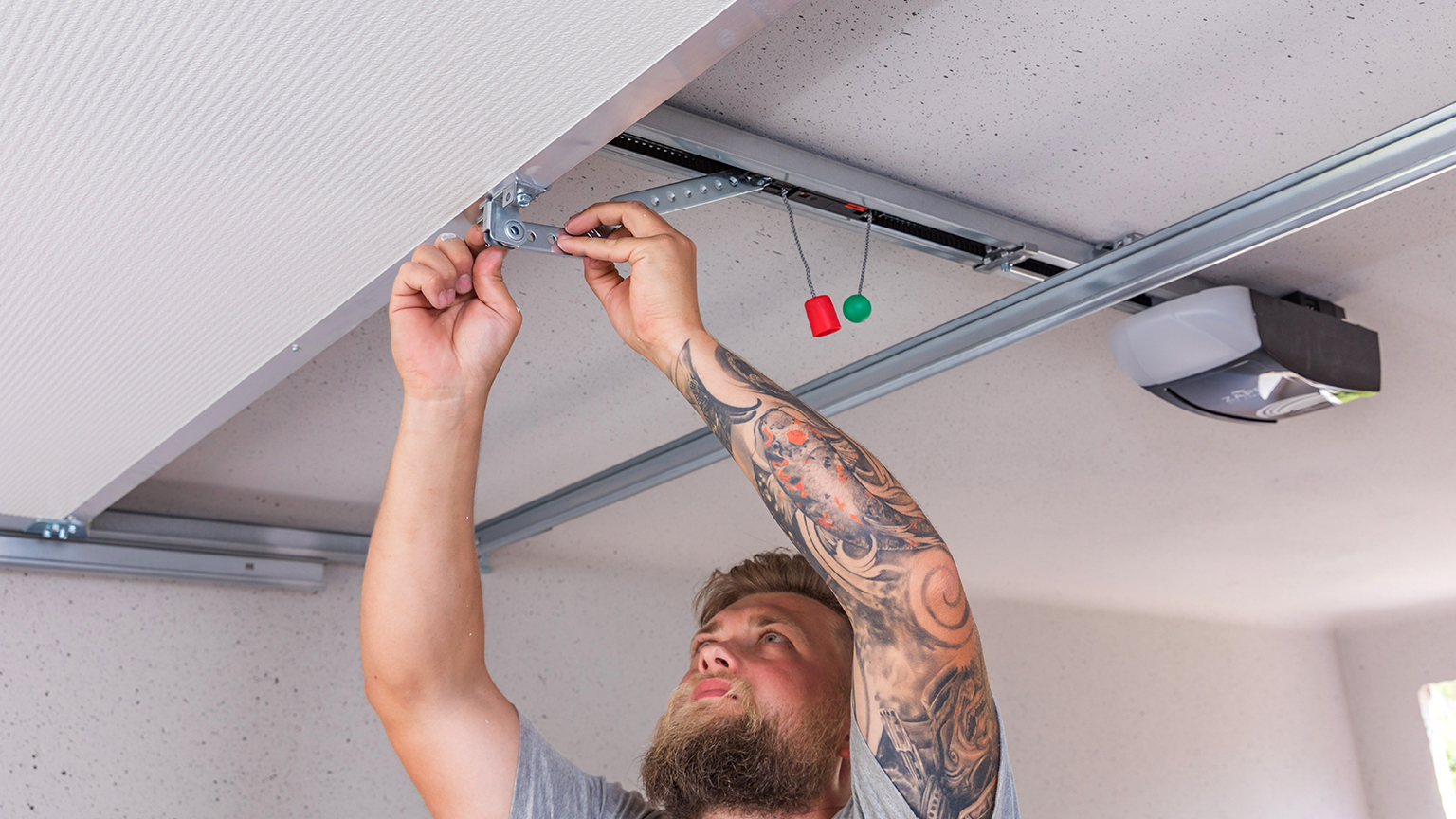 Handwerker montiert Beschlag an einem Garagentor mit elektrischem Antrieb.