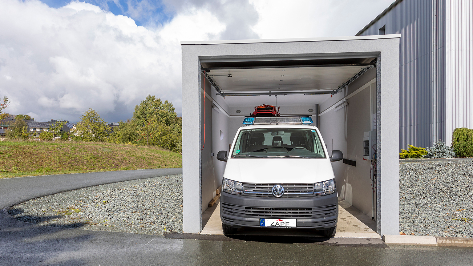 zapf_blog_beitragstitel_traumauto Einsatzfahrzeug parkt in moderner Garage mit halb geöffnetem Sektionaltor.
