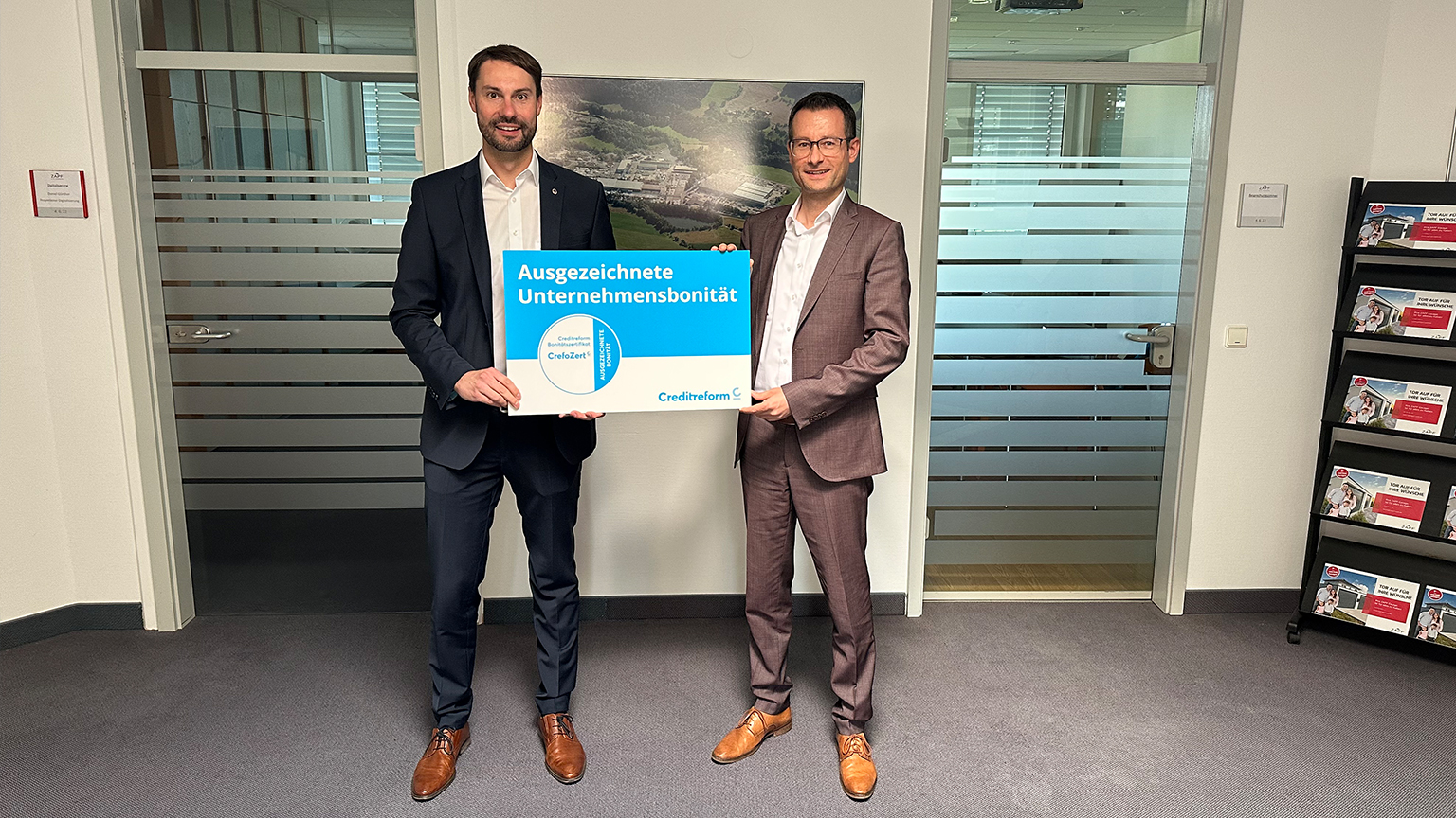 Zwei Männer im Anzug halten eine Auszeichnung von Creditreform für „Ausgezeichnete Unternehmensbonität“ in den Händen.