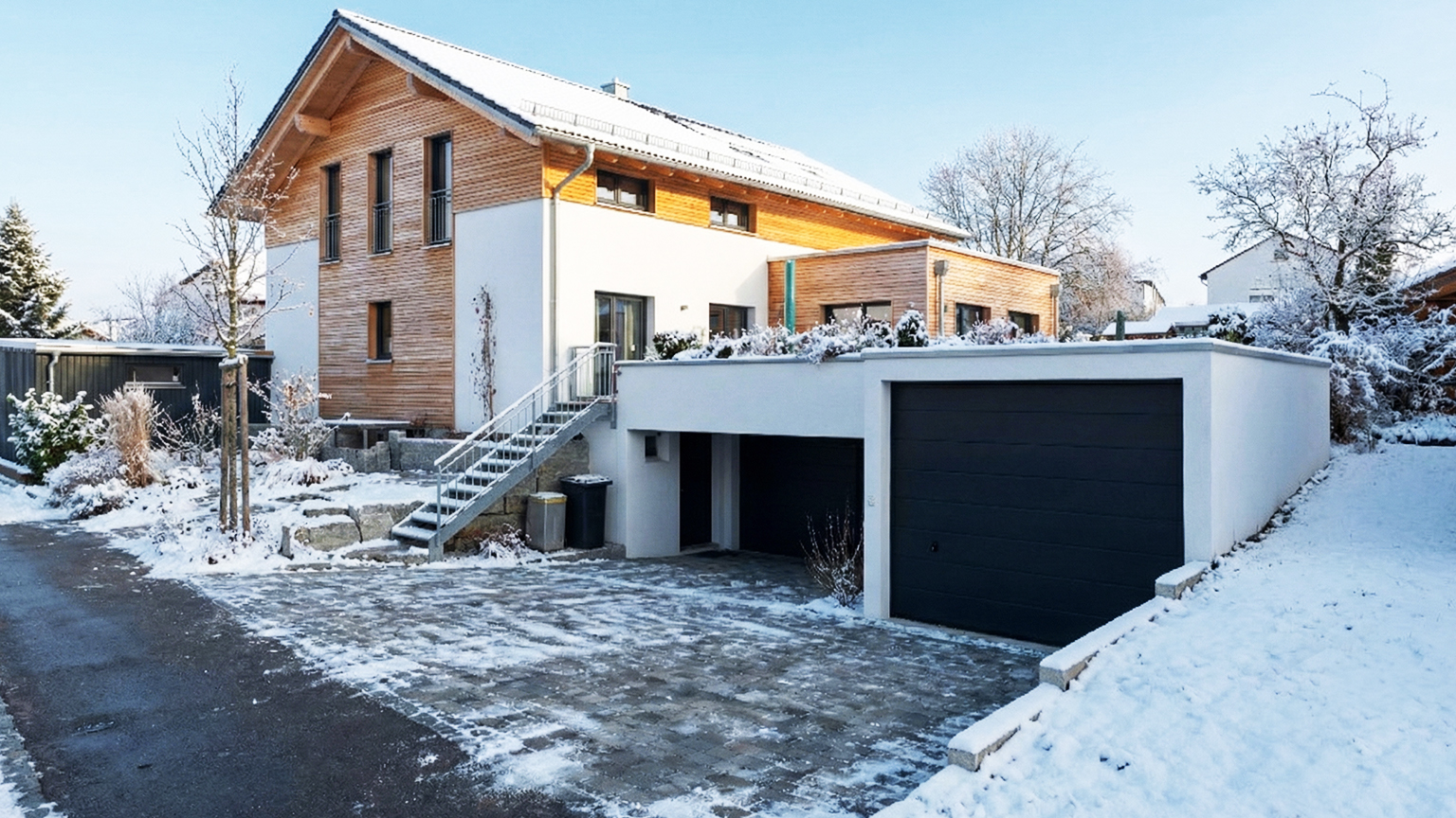 zapf_blog_beitragstitel_landesbauordnung_2 Modernes Wohnhaus mit integrierter Einzelgarage aus Beton im Winter, schneebedeckte Einfahrt und anthrazitfarbenes Garagentor.