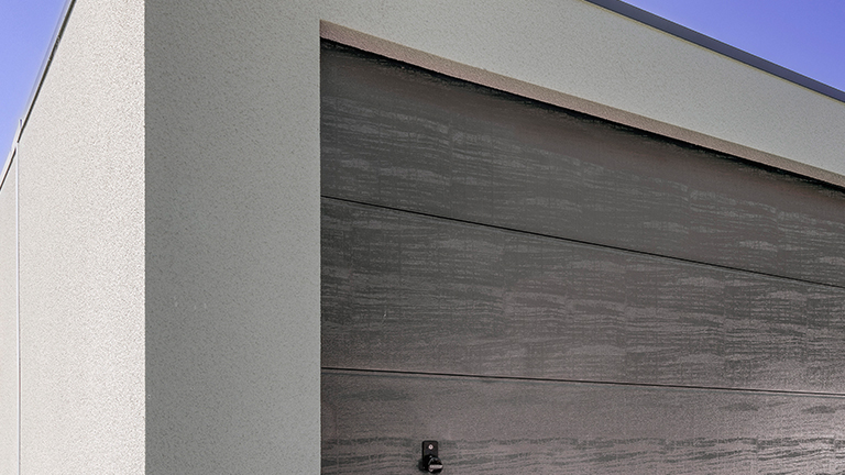 ZAPF Großraumrage mit Sektionaltor in anthrazit. Der Putz ist weiß und ist Grobkornputz.