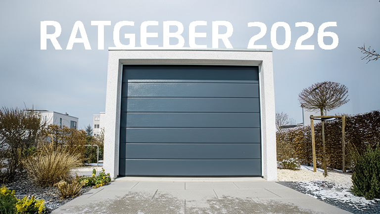 Frontansicht einer freistehenden Betonfertiggarage mit weißer Putzoberfläche und geschlossenem, horizontal gegliedertem grauem Sektionaltor, eingebettet in eine modern gestaltete Außenanlage mit gepflasterter Zufahrt und Bepflanzung, von ZAPF.