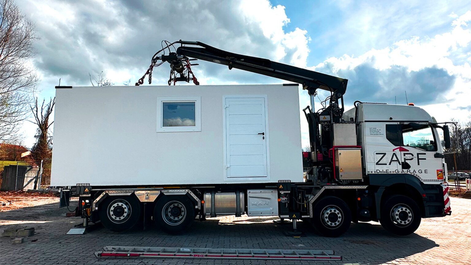 Garage préfabriqué en béton livré clés en main – solution rapide Transport d’un module en béton préfabriqué par camion-grue