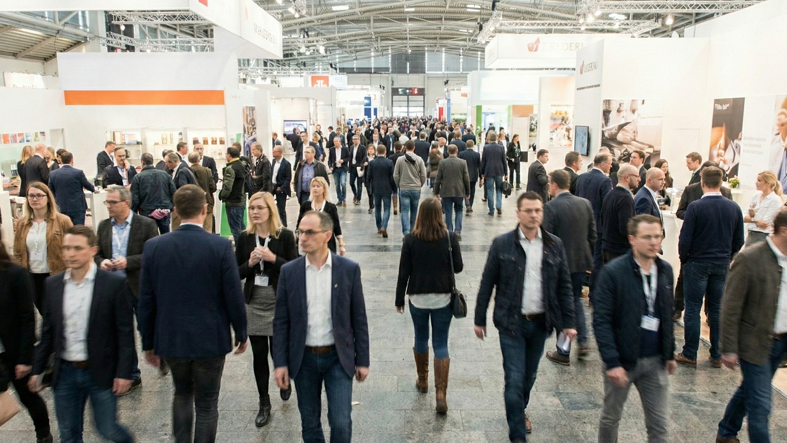 Visitors at a busy trade fair in a modern exhibition hall Numerous visitors walking between brightly designed exhibition booths in a large exhibition hall with wide aisles, information counters and presentation areas, lively atmosphere at an industry trade fair by ZAPF Garagen