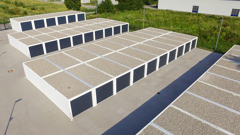 Luftaufnahme einer großflächigen Anlage mit weißen Betonfertiggaragen in Reihen, Flachdächer mit Kiesauflage und gleichmäßig angeordnete dunkle Garagentore auf befestigter Fläche von ZAPF