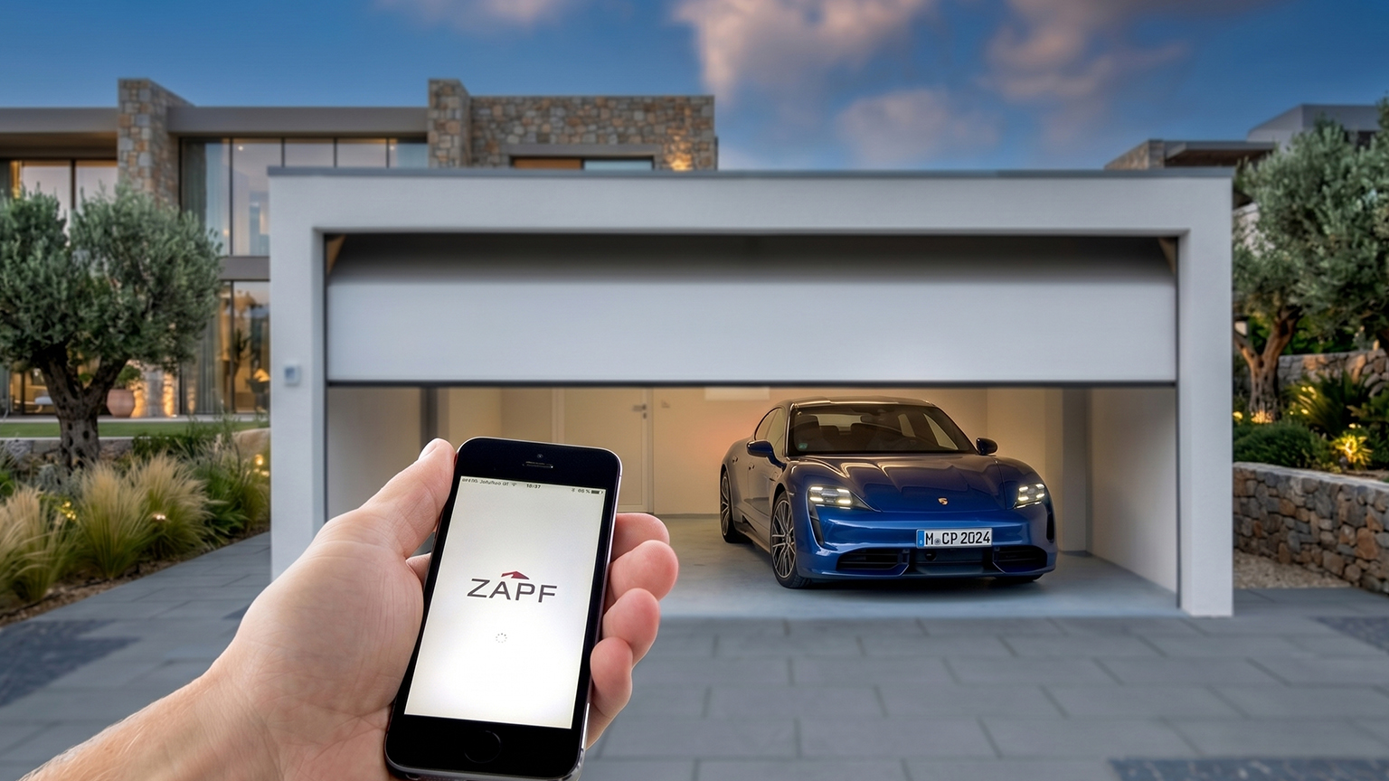 Commande par smartphone d’un garage préfabriqué moderne Une main tient un smartphone avec le logo ZAPF devant un garage préfabriqué en béton moderne avec une porte de garage ouverte et une voiture bleue à l’intérieur, par ZAPF