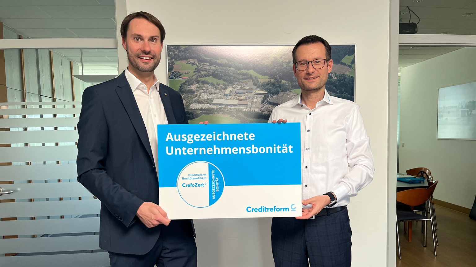 Auszeichnung für Unternehmensbonität von Creditreform Zwei Männer halten in einem Büro eine Creditreform-Auszeichnung für ausgezeichnete Unternehmensbonität mit CrefoZert-Bonitätszertifikat von ZAPF